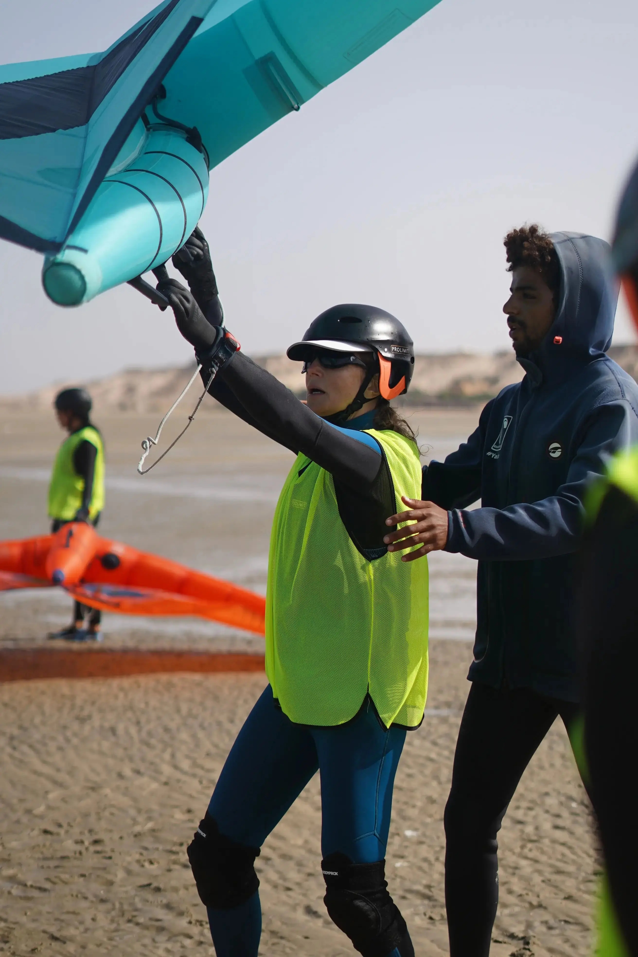 Bluboarding wingfoil instructor explaining wing technique to a group of students on the water of the Dakhla lagoon during a group wingfoil lesson.