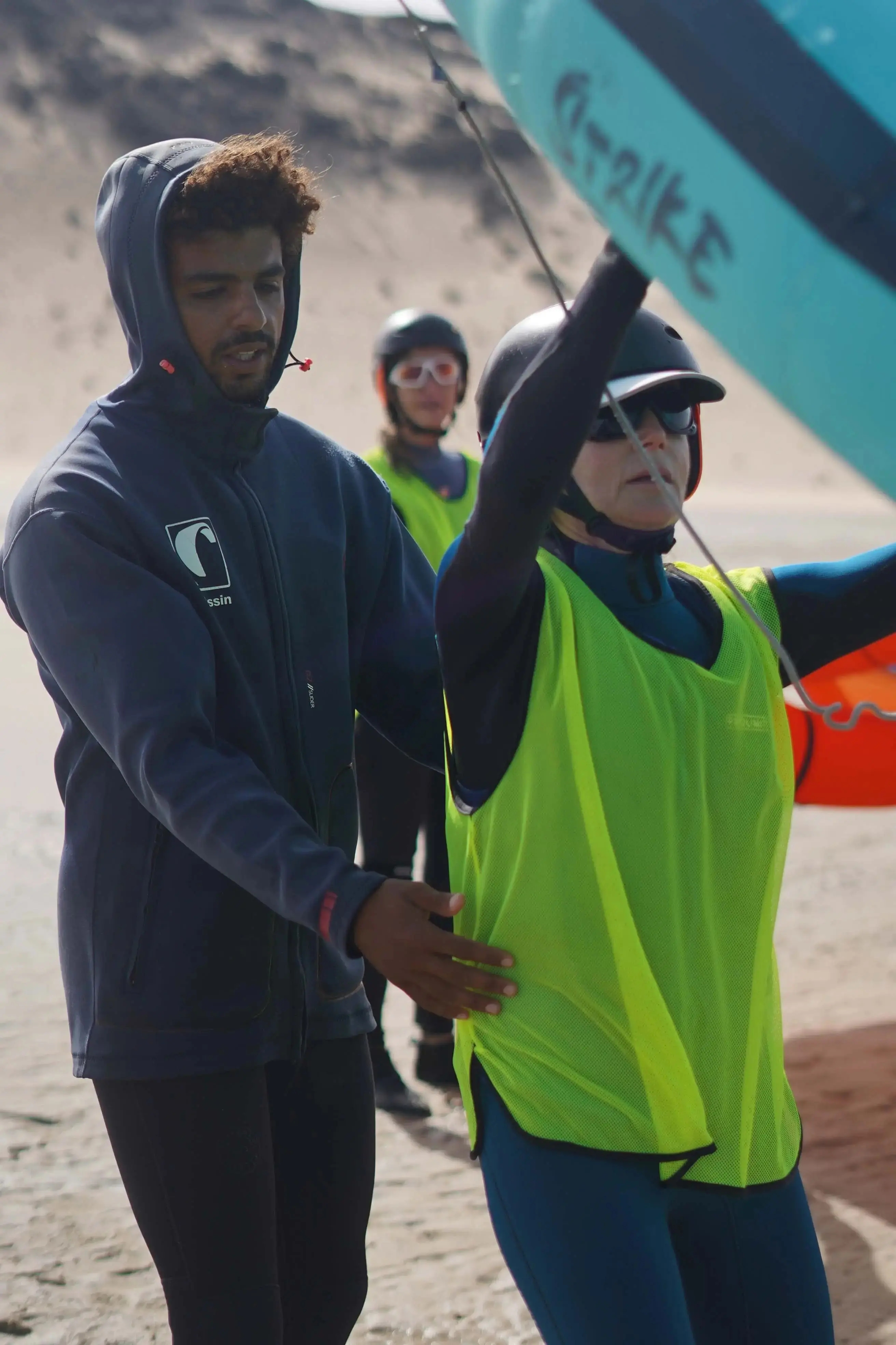 Bluboarding wingfoil instructor explaining wing handling to two students on the water of the Dakhla lagoon during a semi-private wingfoil lesson.