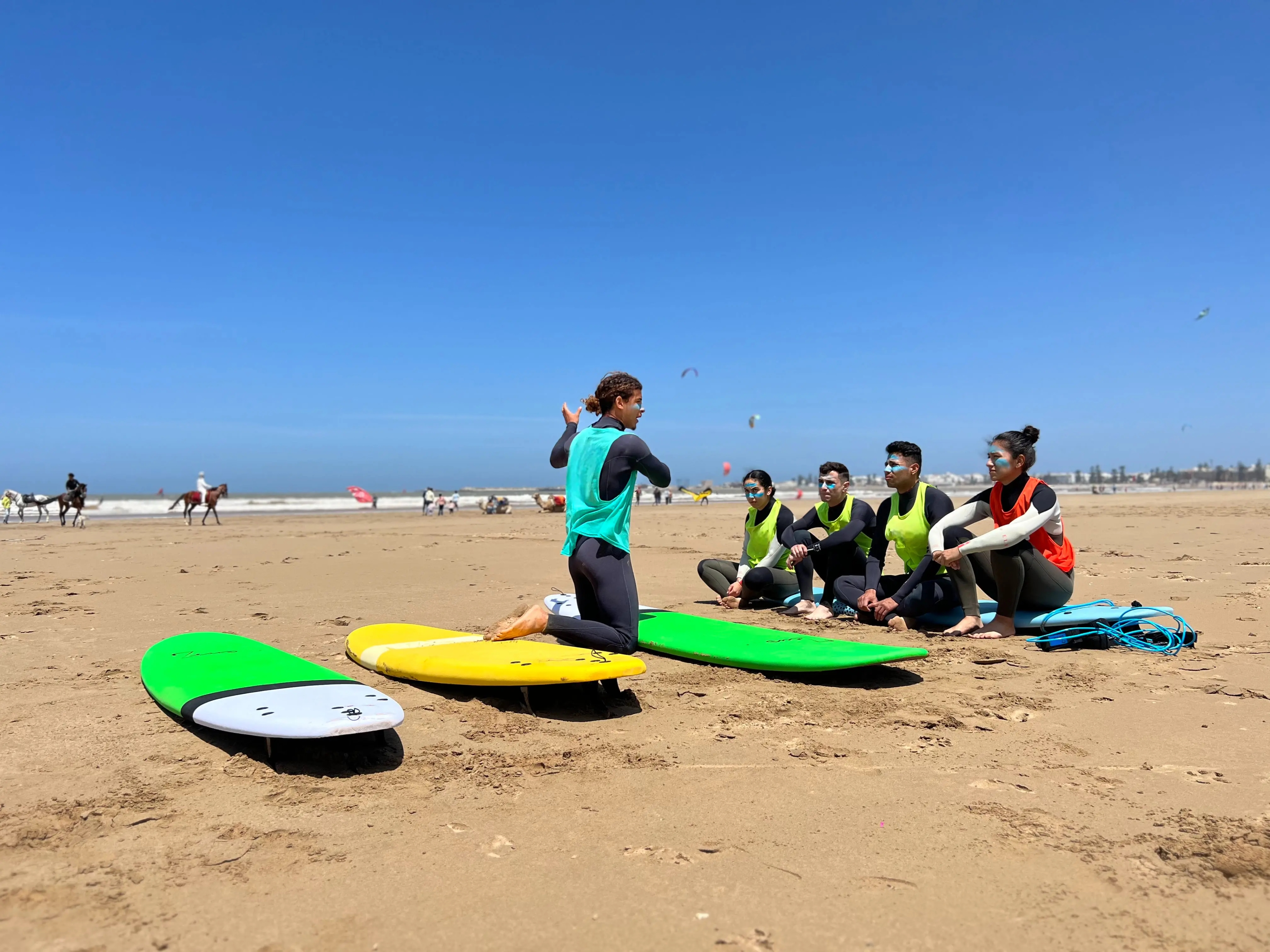 An instructor explaining wave theory to two friends on the beach before their semi-private surf lesson in Dakhla.