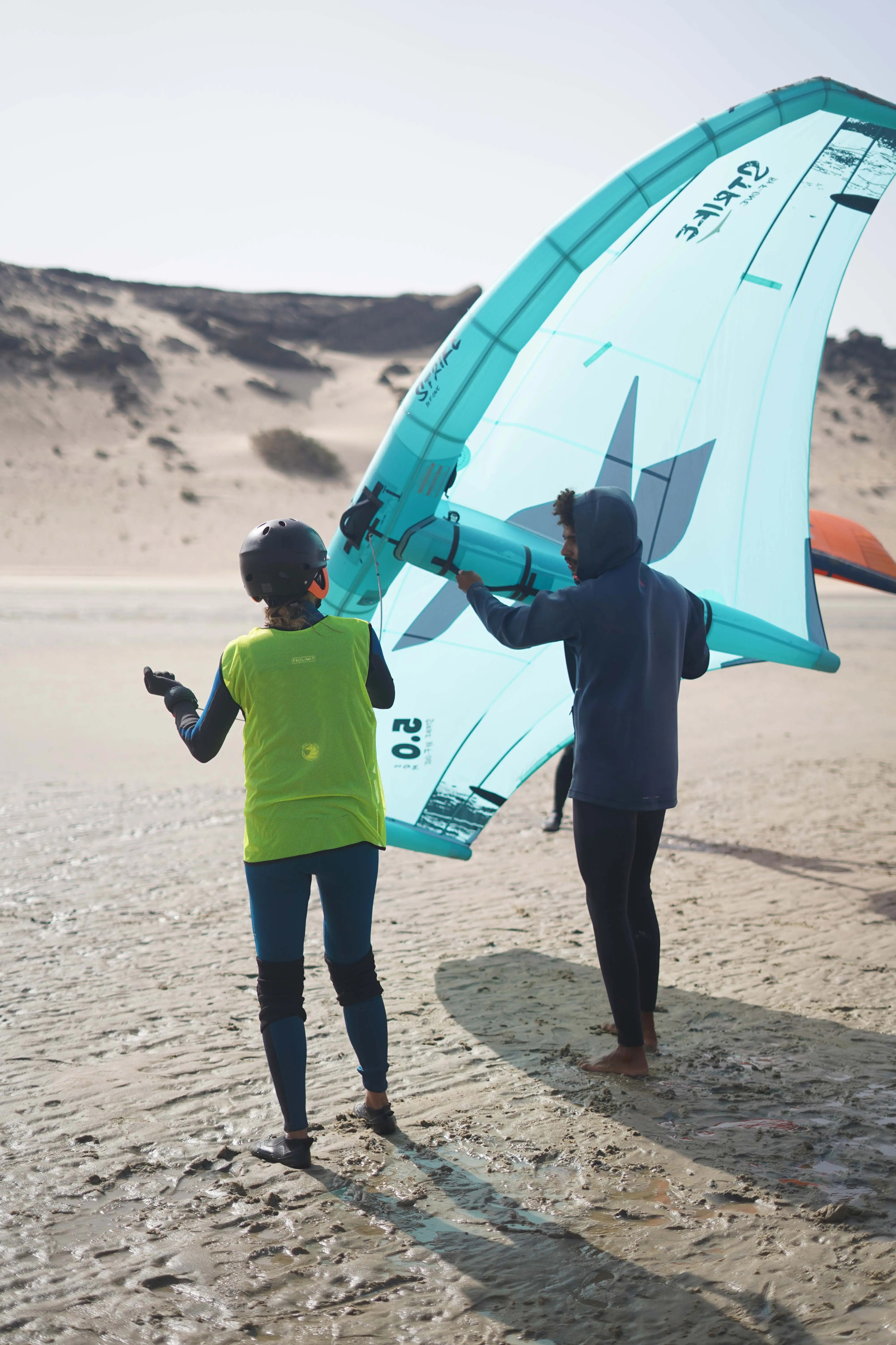 A Bluboarding instructor giving a private wingfoil lesson, teaching a student how to handle the wing on Dakhla's beach.