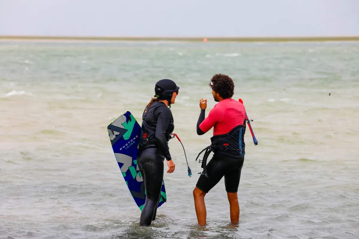 Bluboarding kitesurf instructor explaining jump landing technique to a student on the flat water of the Dakhla lagoon in Morocco.
