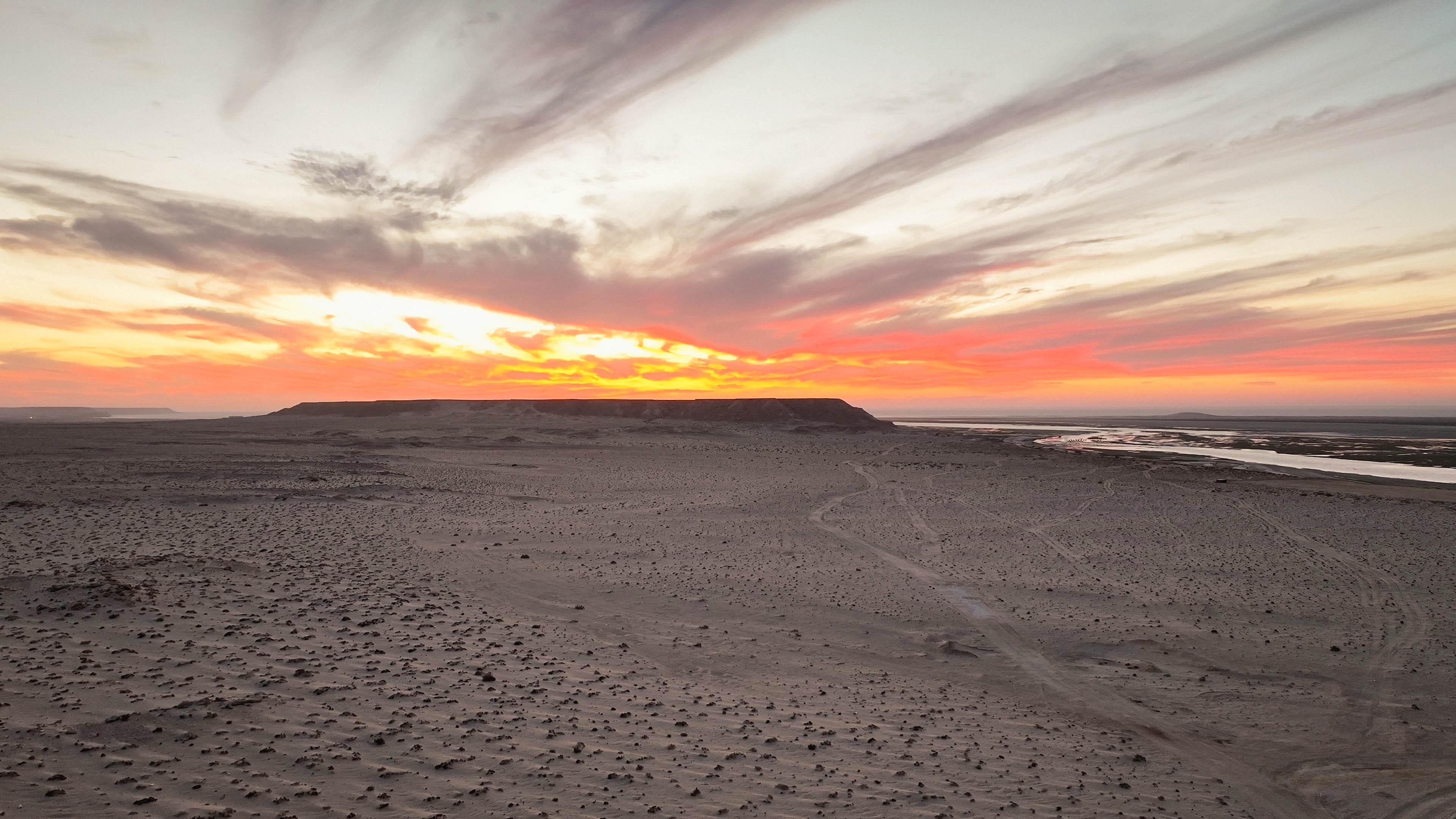 Sunset over the Dakhla desert with the White Dune visible in the distance across the lagoon, a starting point for Bluboarding guided excursions.