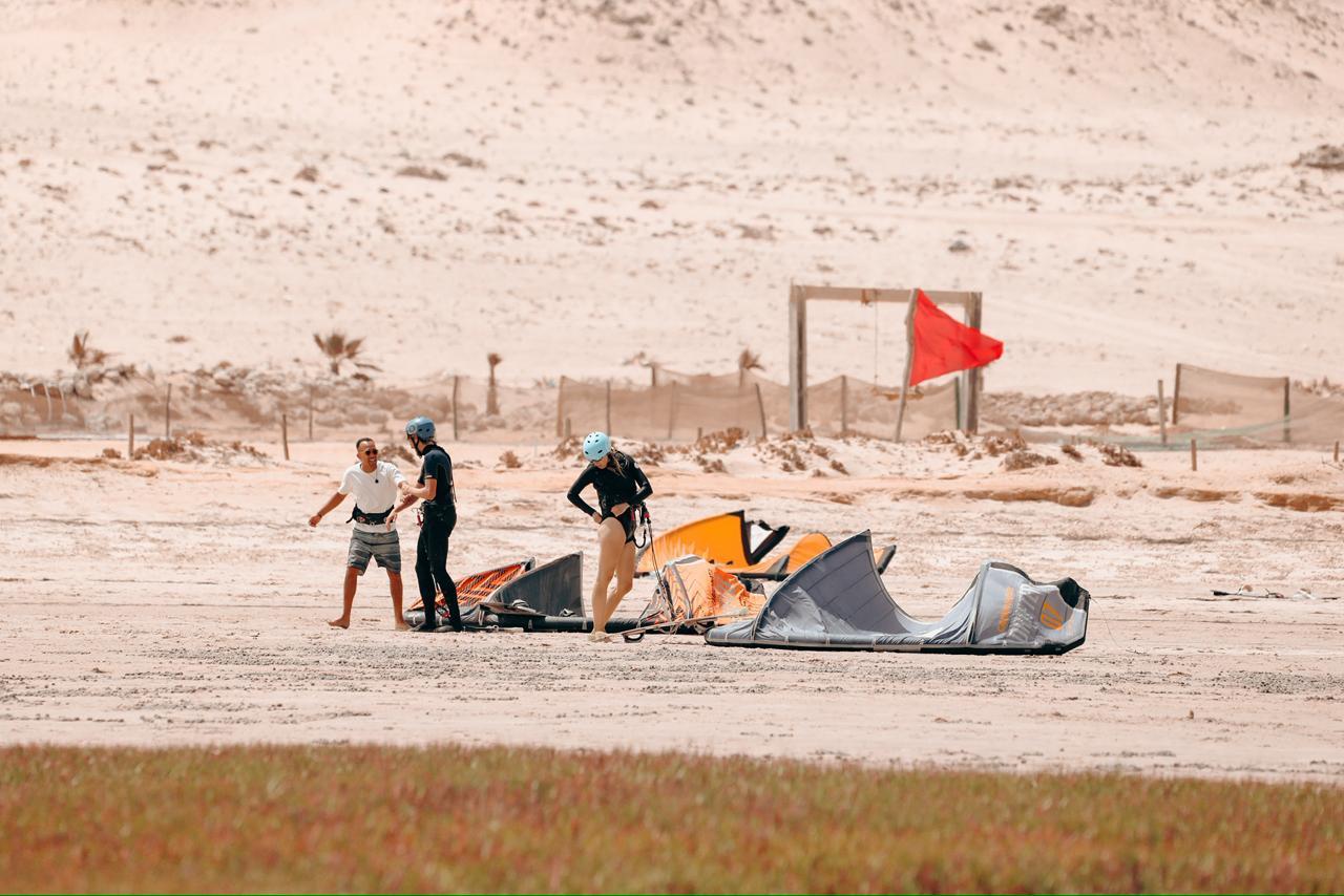 Bluboarding team member sharing a fun moment with kitesurf clients on the shore of the Dakhla lagoon before heading to the water for a kitesurf session.
