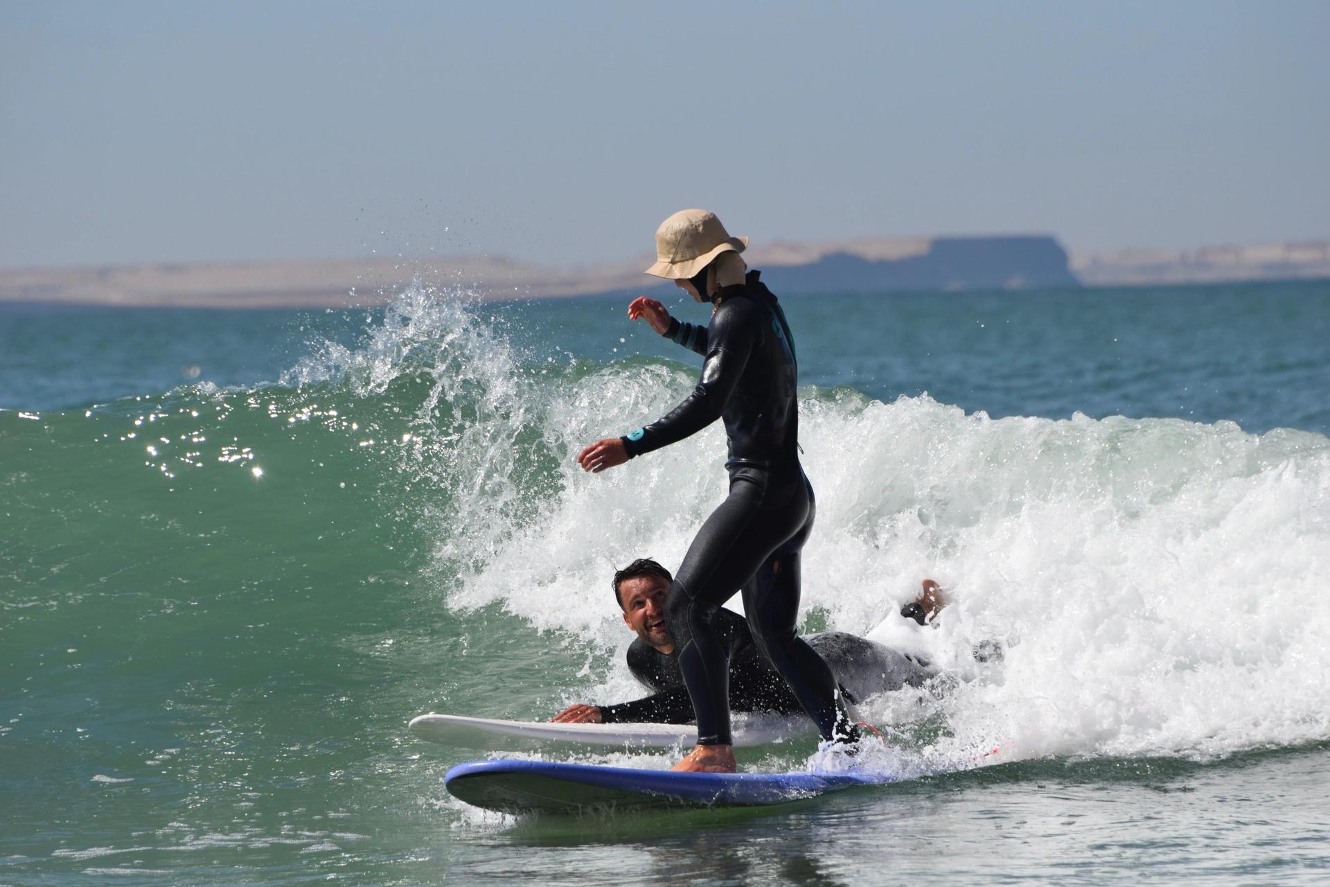 A guy watching a lady catching her first wave in Dakhla with the Bluboarding team.