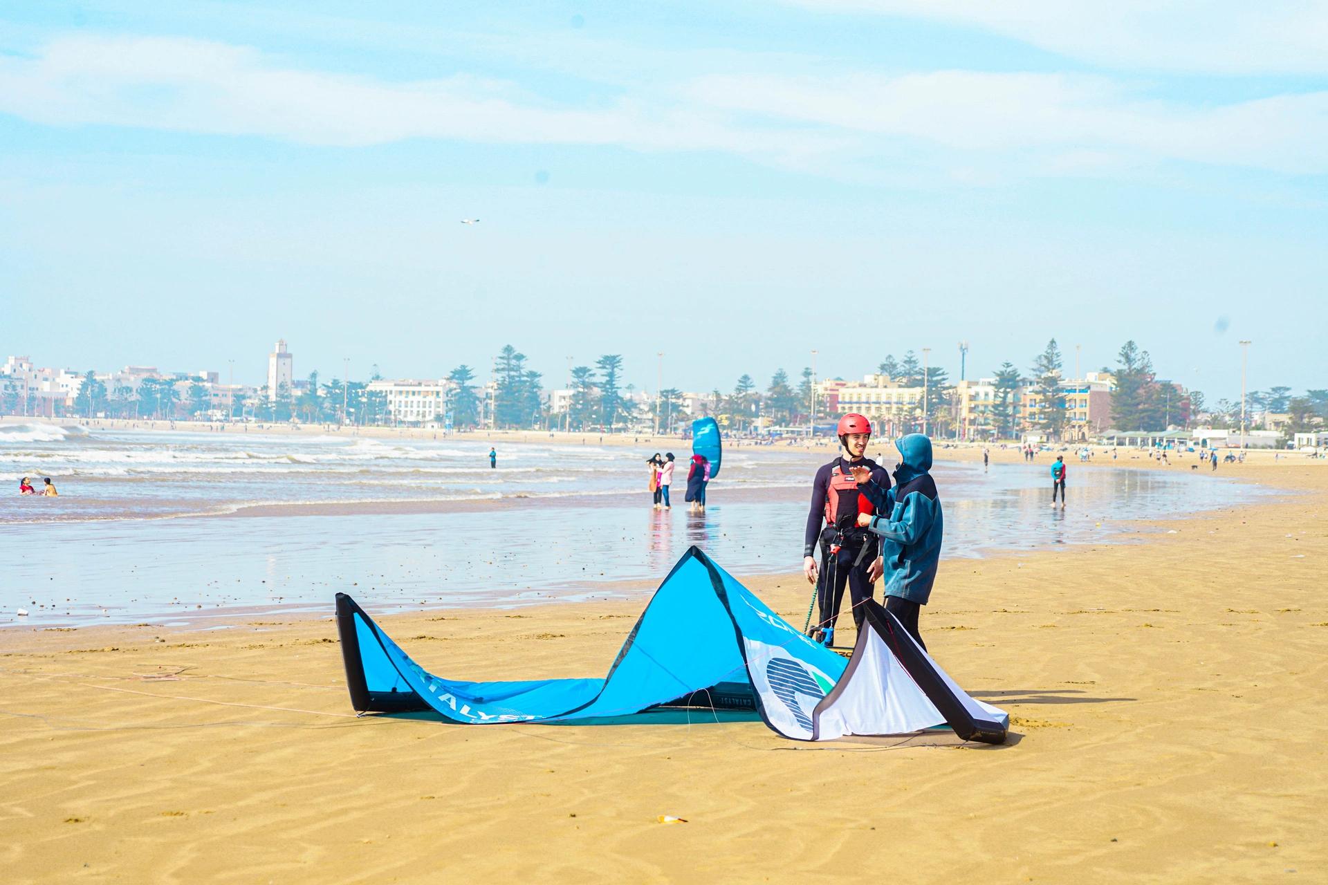 Bluboarding kitesurf instructor explaining the basics to a beginner student on the beach of Essaouira before heading to the water.