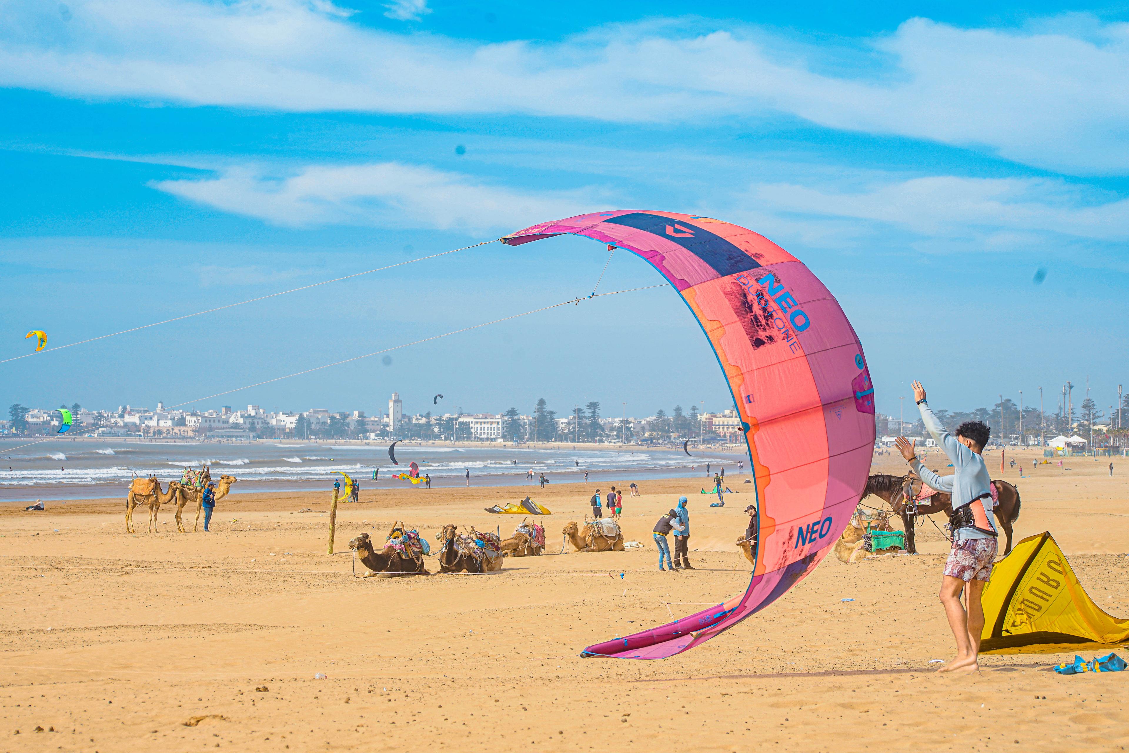 Bluboarding team member helping a client launch the kite on the wide sandy beach of Essaouira before a kitesurf lesson.
