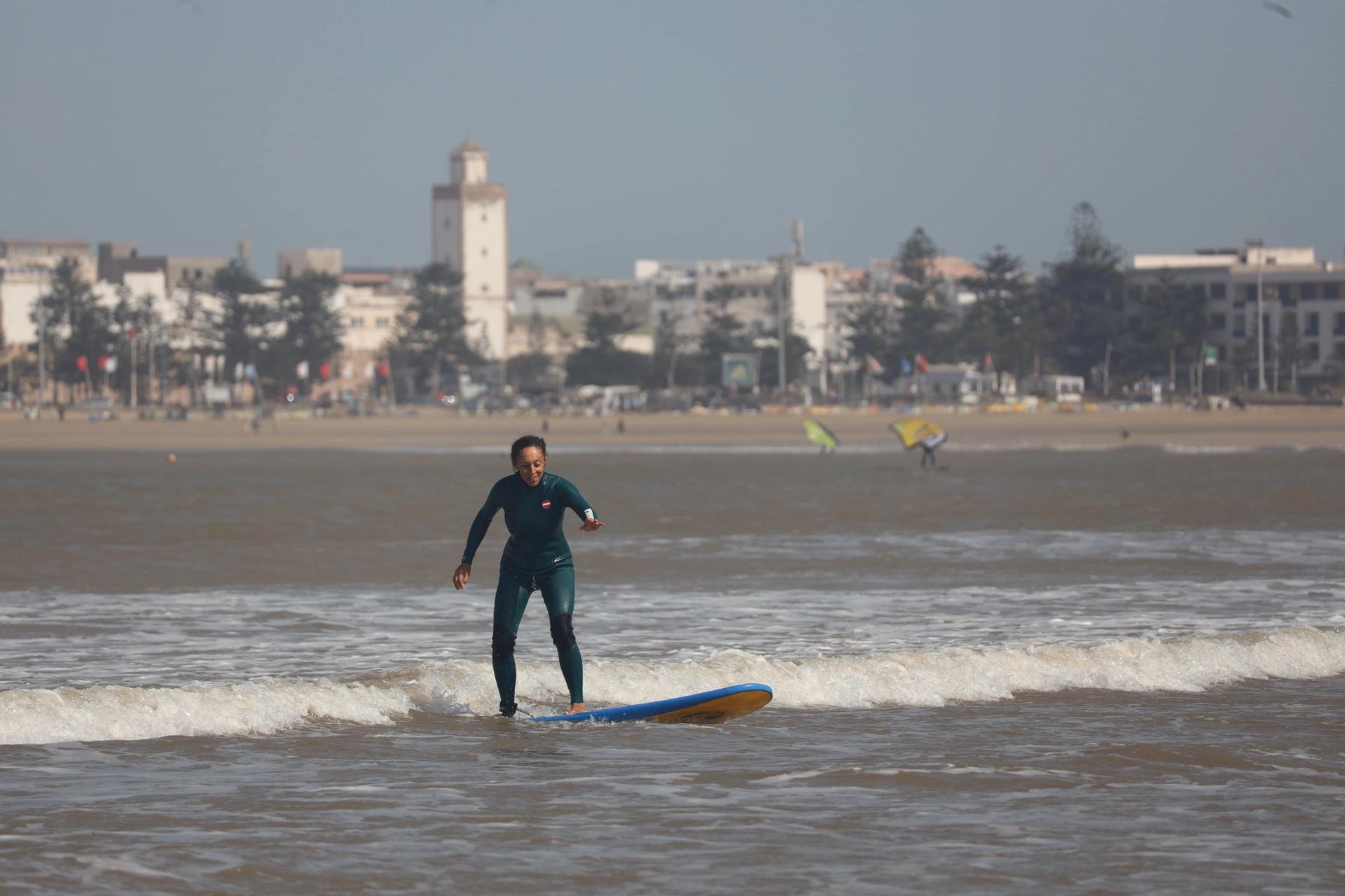 Bluboarding client catching a small wave with a smile during a surf lesson on the main beach of Essaouira.