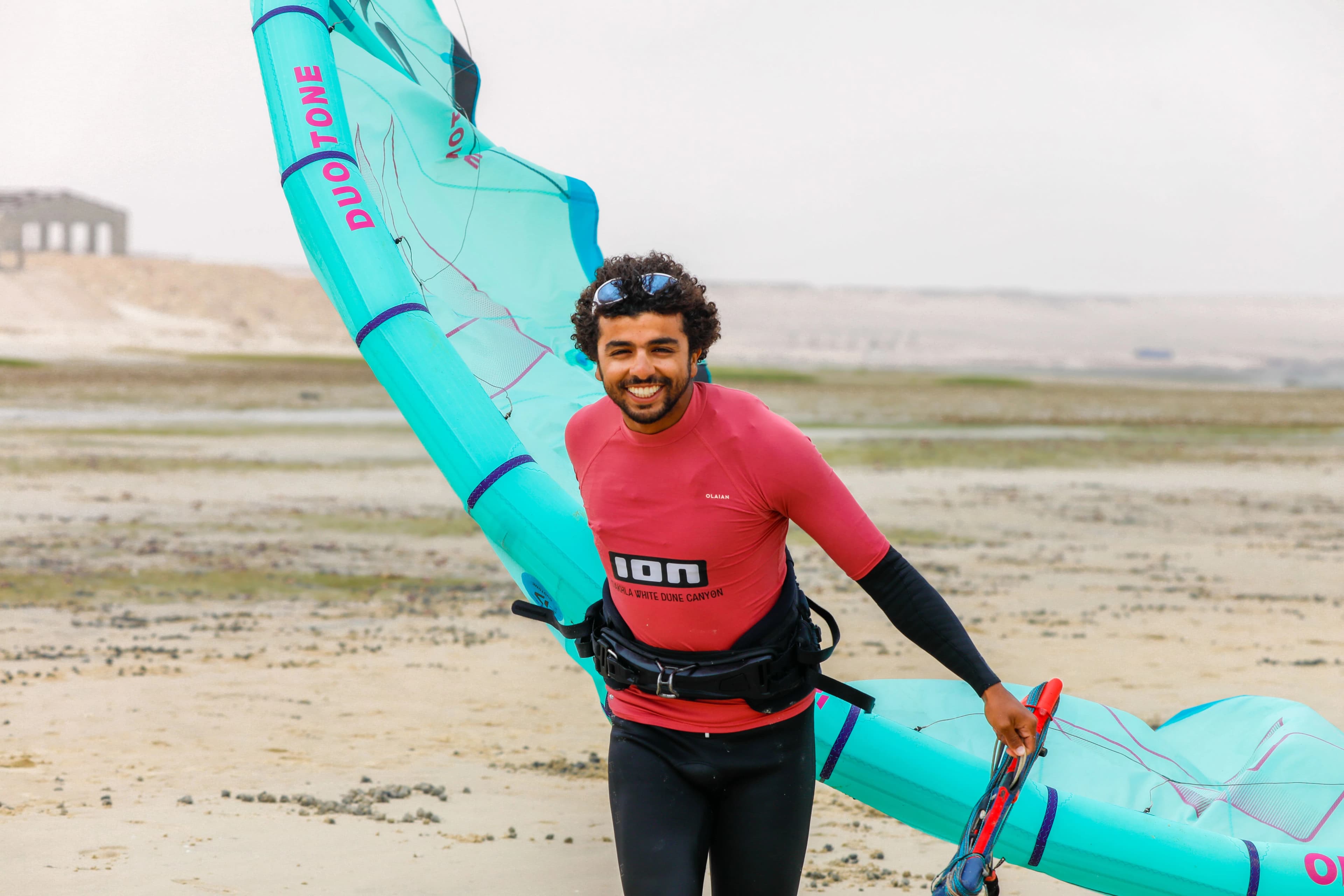 A smiling Bluboarding instructor in the Dakhla water, ready to share the passion of kitesurfing with a student.